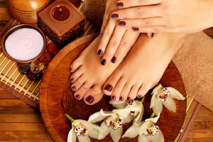 Closeup photo of a female feet at spa salon on pedicure procedure. Female legs in water decoration  the flowers.